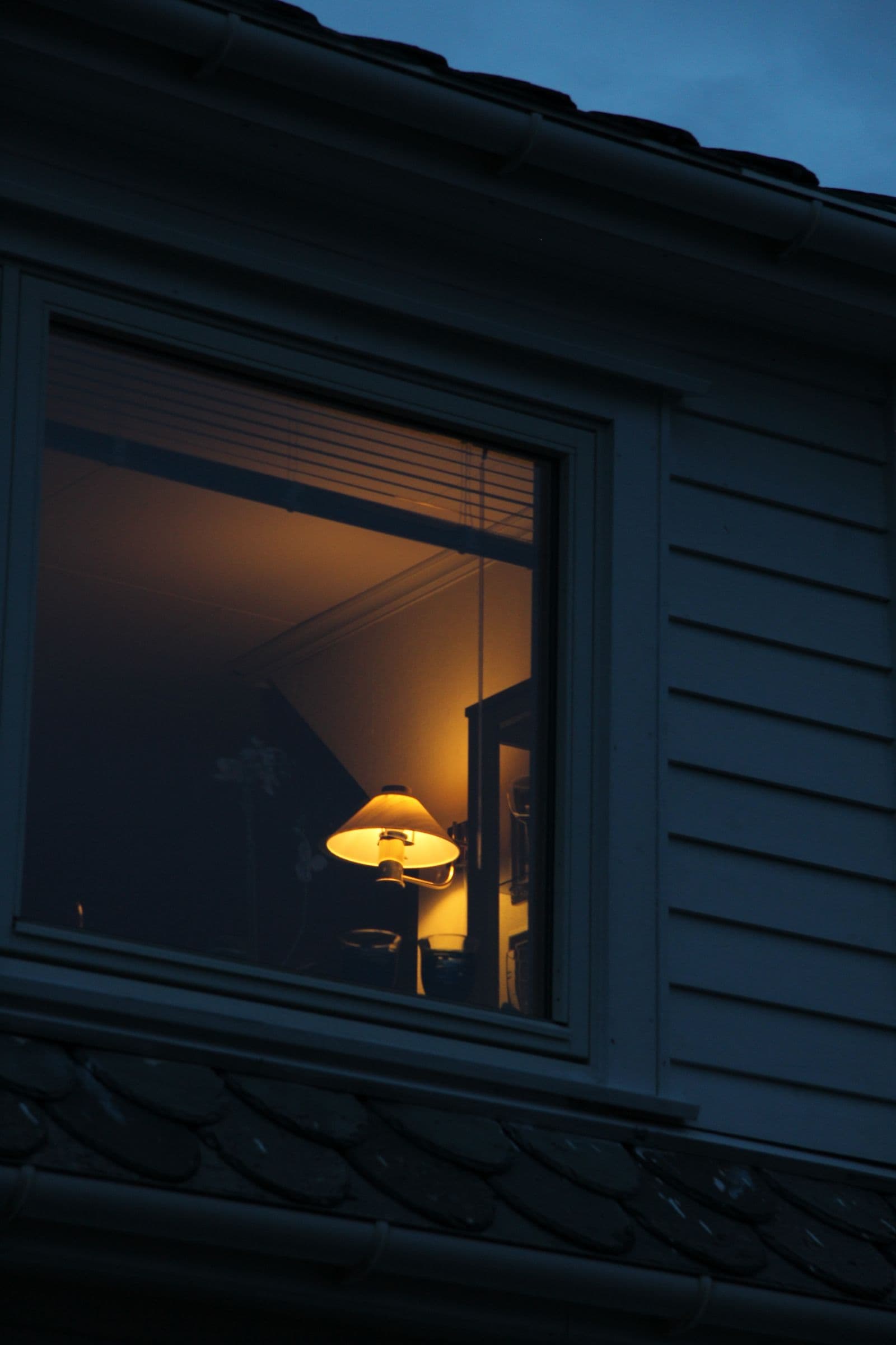 Une fenêtre éclairée d'une lumière chaude, dans la nuit